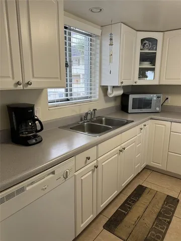 a kitchen with white cabinets and sink