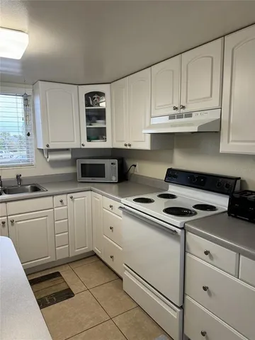 a kitchen with granite countertop white cabinets and white appliances