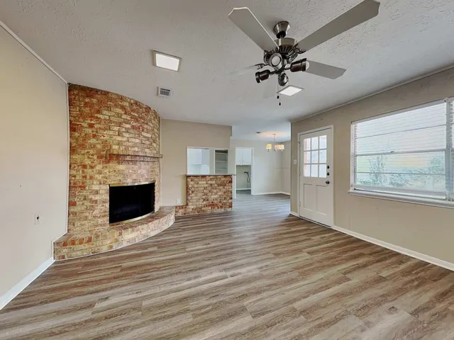a view of a livingroom with a fireplace a ceiling fan and wooden floor