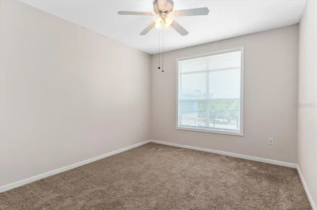 an empty room with a ceiling fan and a window