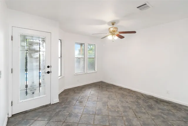 an empty room with windows and fan