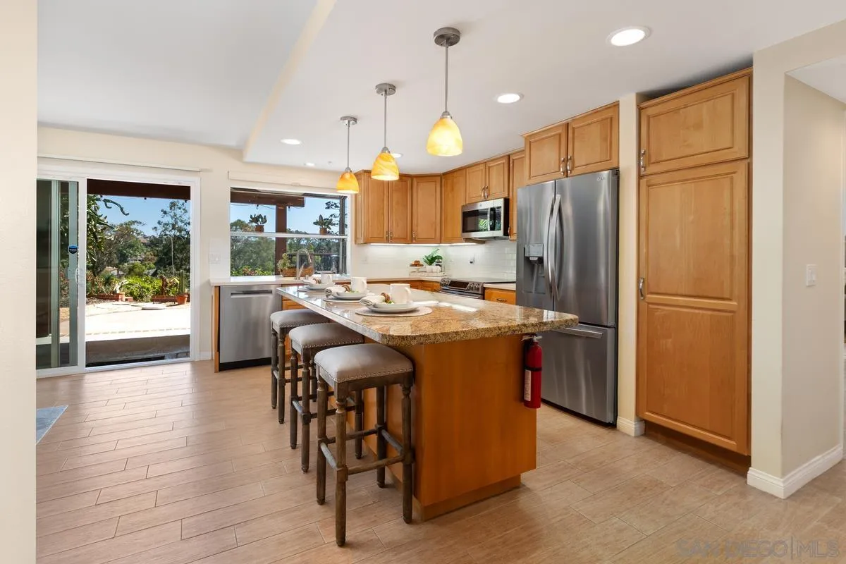 4219 Rueda Drive San Diego, CA 92124 - Photo 12 of 36 a kitchen with stainless steel appliances granite countertop a refrigerator a sink dishwasher a dining table and chairs with wooden floor
