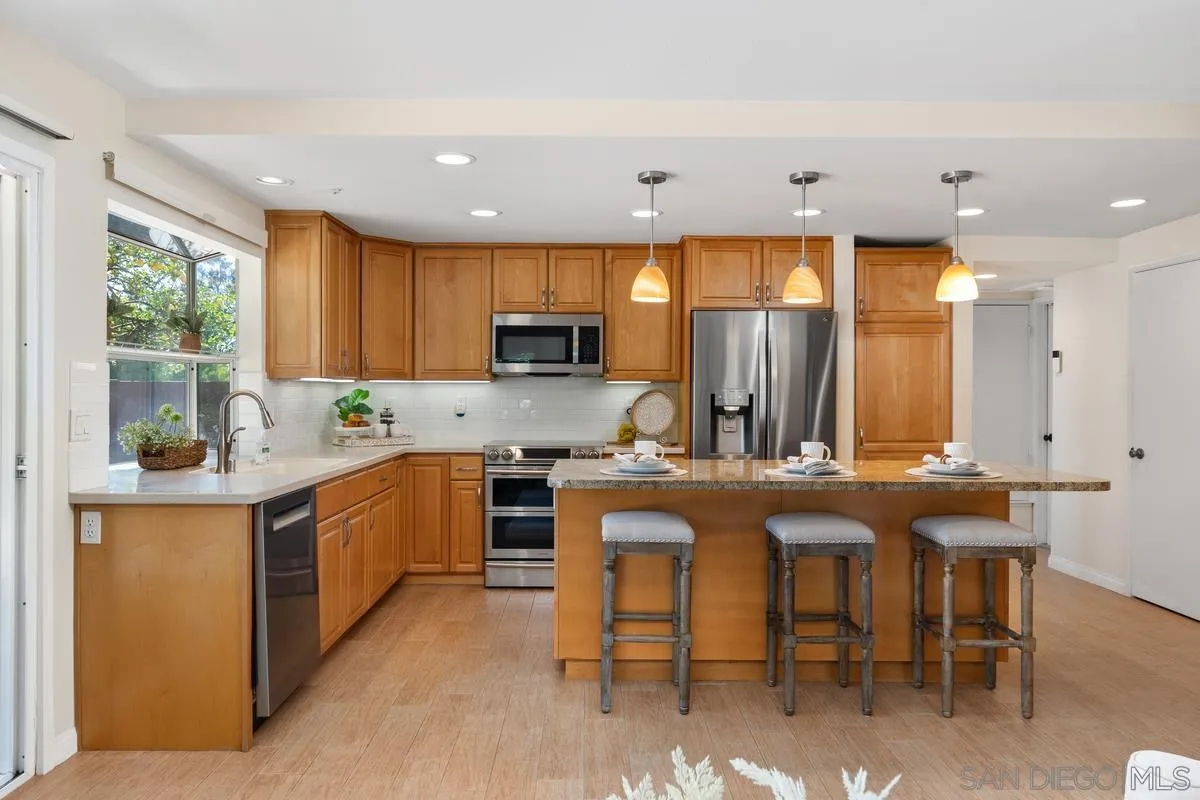 4219 Rueda Drive San Diego, CA 92124 - Photo 13 of 36 a kitchen with kitchen island granite countertop wooden cabinets and stainless steel appliances