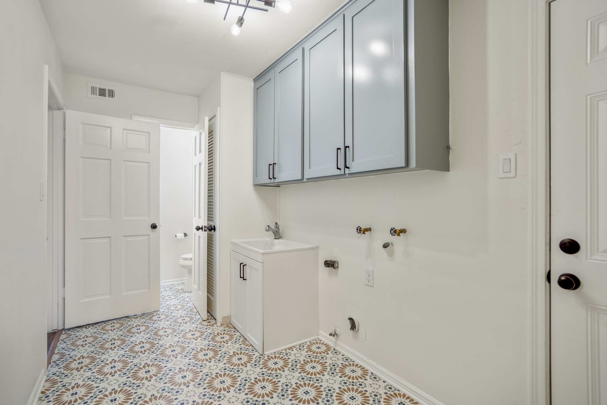 8006 Vickridge Lane Spring, TX 77379 - Photo 40 of 50 The downstairs laundry room offers fresh designer flooring, added cabinetry, laundry sink, and updated finishes. Beyond the doorway that connects back to the kitchen area we get a peek into the half bath.