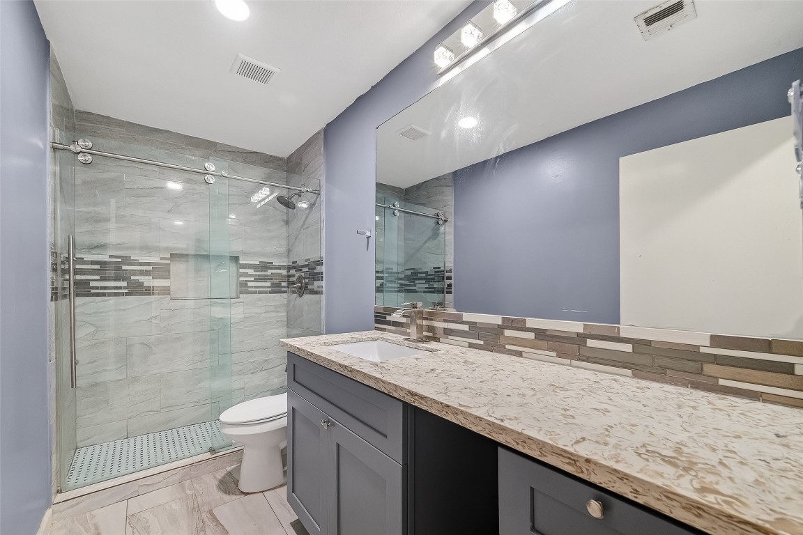 10706 Sagebluff Drive Houston, TX 77089 - Photo 18 of 19 a bathroom with a granite countertop sink a toilet a mirror and shower