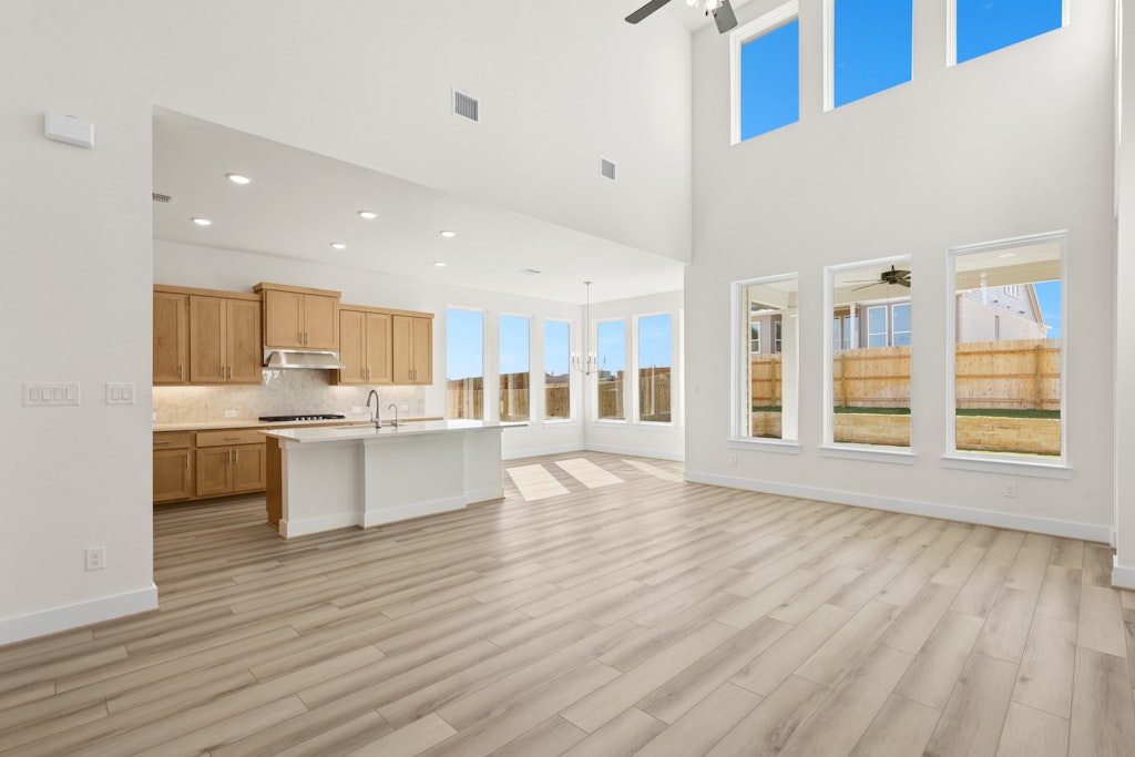 19512 Judys View Pflugerville, TX 78660 - Photo 5 of 38 a large white kitchen with kitchen island a sink wooden floor and a large window