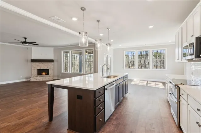 a large kitchen with kitchen island a sink a stove and a wooden floors