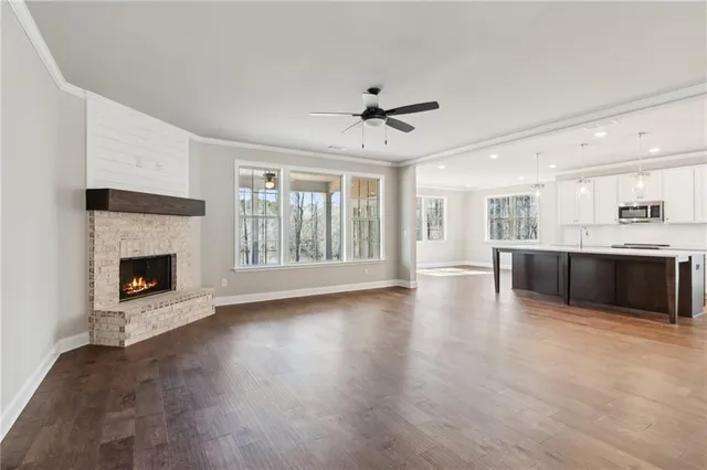 a living room with stainless steel appliances kitchen island a fireplace and wooden floor