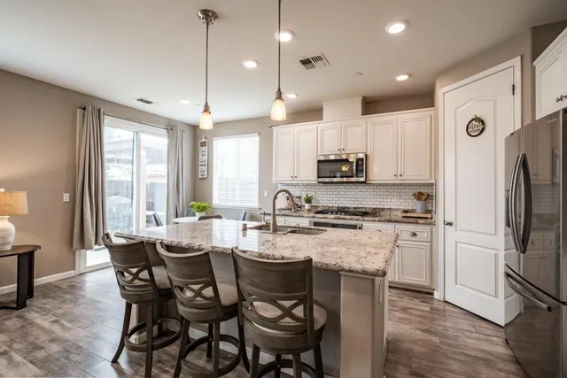 a kitchen with stainless steel appliances granite countertop a stove a refrigerator a kitchen island with a dining table and chairs