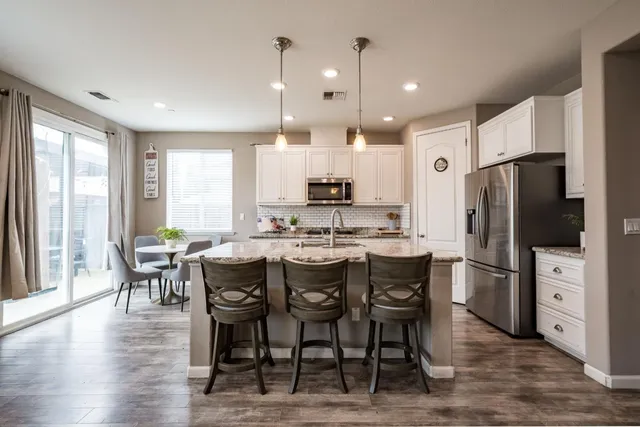 a kitchen with stainless steel appliances granite countertop a table chairs refrigerator and microwave