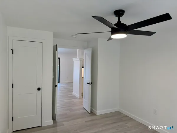 an empty room with wooden floor fan and windows