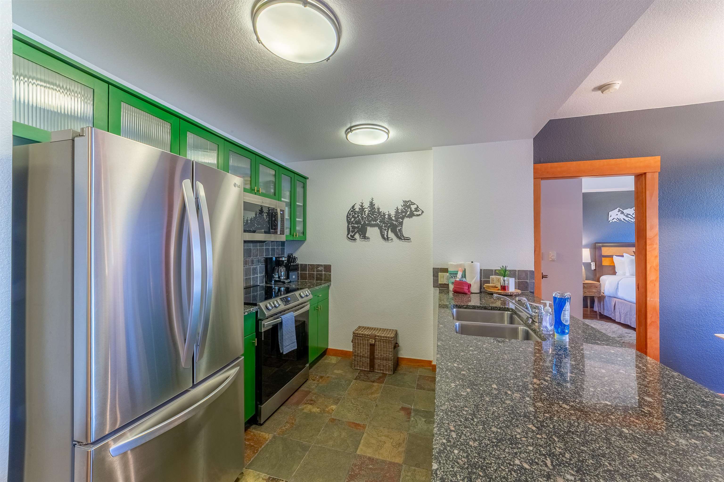 6201 Minaret Road, Unit 2221 Mammoth Lakes, CA 93546 - Photo 4 of 44 Kitchen featuring green cabinetry with reeded glass accents, stainless steel appliances, and a tiled backsplash