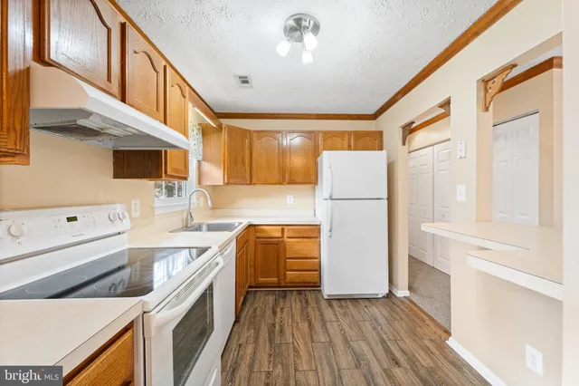 a kitchen with a refrigerator a sink and dishwasher with wooden floor