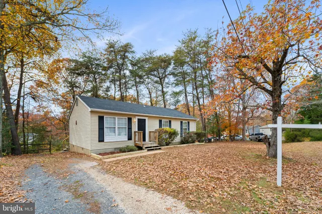 a view of a white house next to a yard with large trees