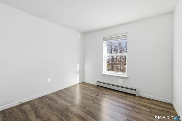 an empty room with wooden floor and window