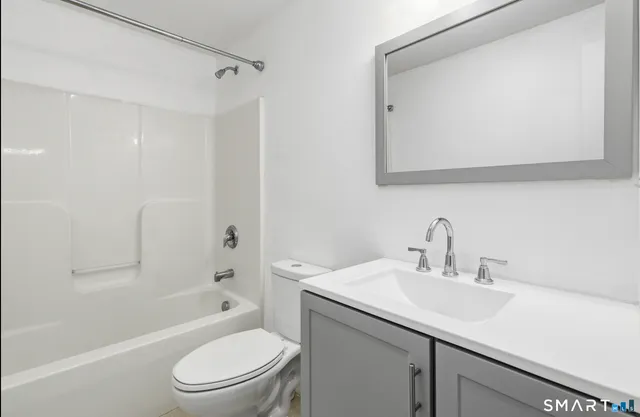 a bathroom with a toilet a sink a mirror a bathtub and vanity