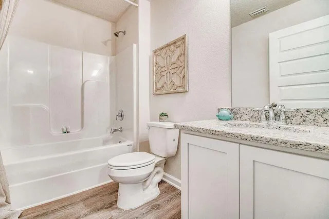 a bathroom with a granite countertop sink toilet and shower