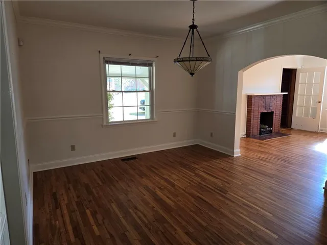 a view of a room with wooden floor fireplace and windows