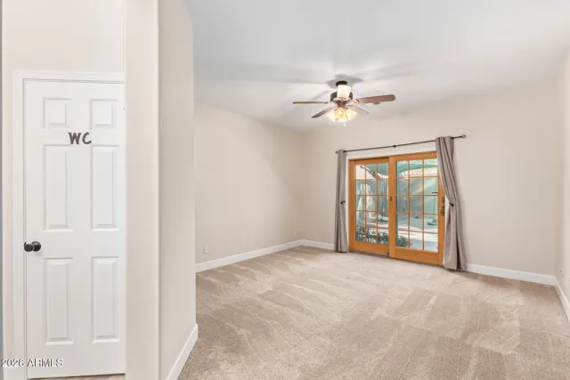 an empty room with chandelier fan and windows