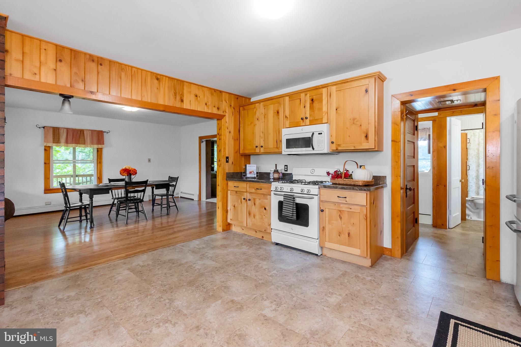 2485 Potomac Road Berkeley Springs, WV 25411 - Photo 9 of 60 a kitchen with stainless steel appliances granite countertop a stove top oven a sink a dining table and chairs with wooden floor