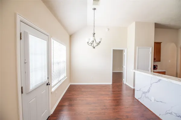 a view of a hallway with wooden floor and a chandelier