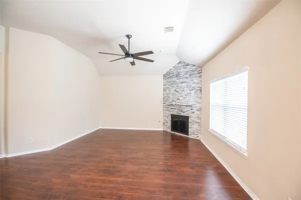 a view of a livingroom with a fireplace a ceiling fan and window