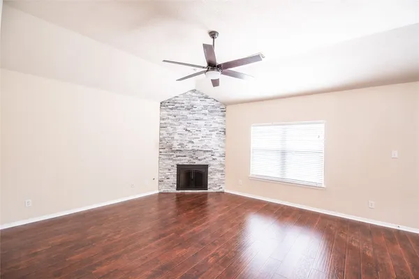 an empty room with wooden floor fan and windows