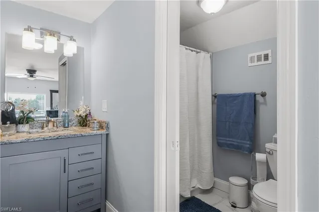 a bathroom with a granite countertop sink toilet and mirror