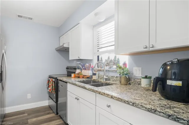 a kitchen with granite countertop a sink stainless steel appliances and cabinets