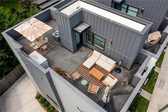 a front view of multi story residential apartment building with large trees and plants