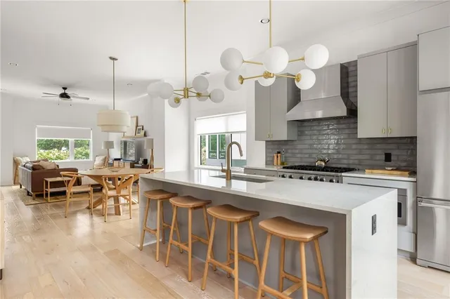 a kitchen with stainless steel appliances granite countertop a stove a sink a dining table chairs and chandelier