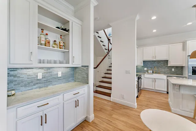 a kitchen with granite countertop a stove a sink a dining table and chairs with wooden floor