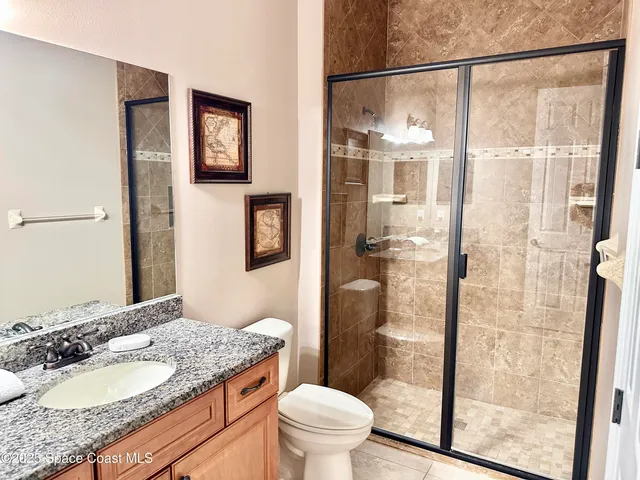 a bathroom with a granite countertop sink toilet and shower
