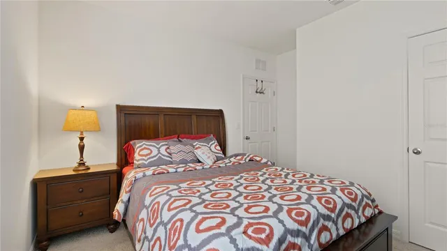 a bedroom with a bed and a lamp on dresser