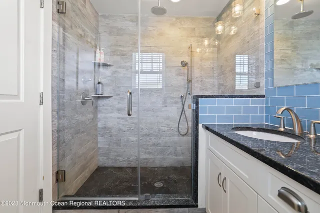 a bathroom with a granite countertop sink a mirror and shower