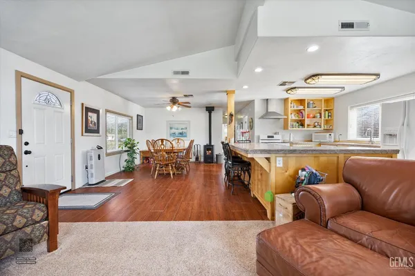 a living room with furniture kitchen view and a wooden floor