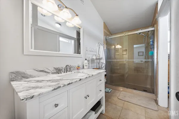 a bathroom with a granite countertop sink a mirror and a shower