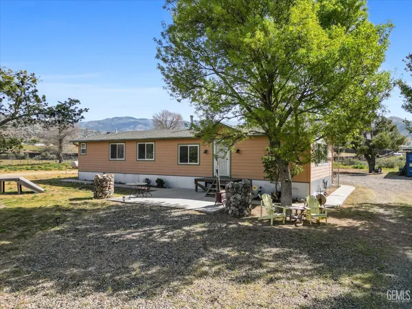 a backyard of a house with table and chairs under an umbrella