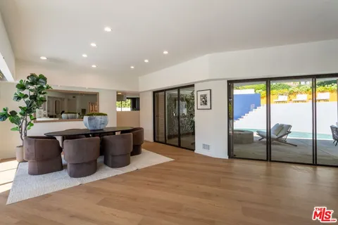 a kitchen with stainless steel appliances kitchen island granite countertop a refrigerator a sink a stove and a wooden floors