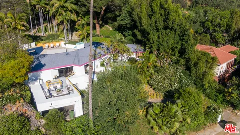 an aerial view of residential house with outdoor space and trees all around
