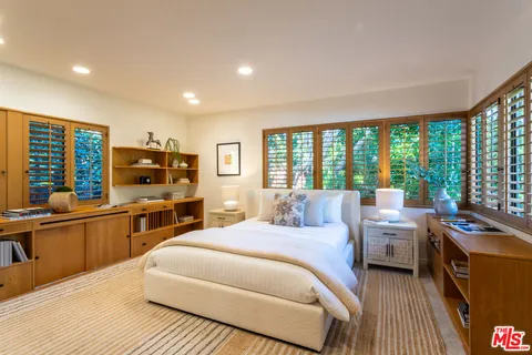 a room with a bed and large windows