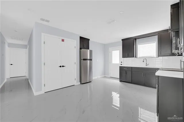 a large white kitchen with a sink and refrigerator