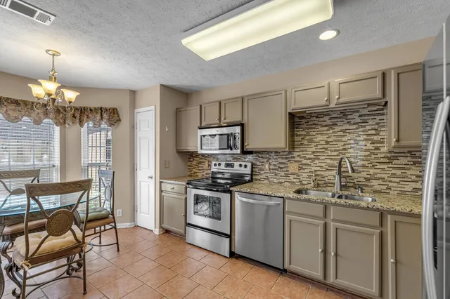 a kitchen with stainless steel appliances granite countertop a stove top oven a sink dishwasher and a refrigerator