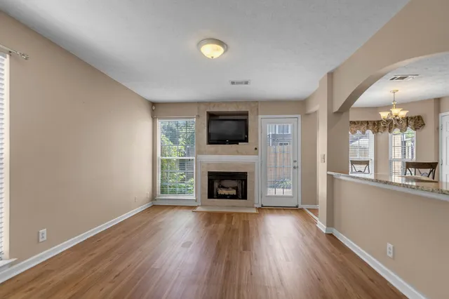 an empty room with windows a fireplace and wooden floor
