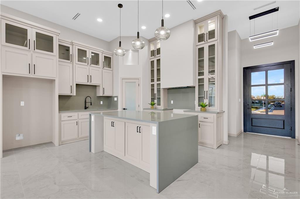 608 Spring Drive Alton, TX 78573 - Photo 12 of 32 Kitchen with glass insert cabinets, a center island, hanging light fixtures, light marble finish floors, and recessed lighting