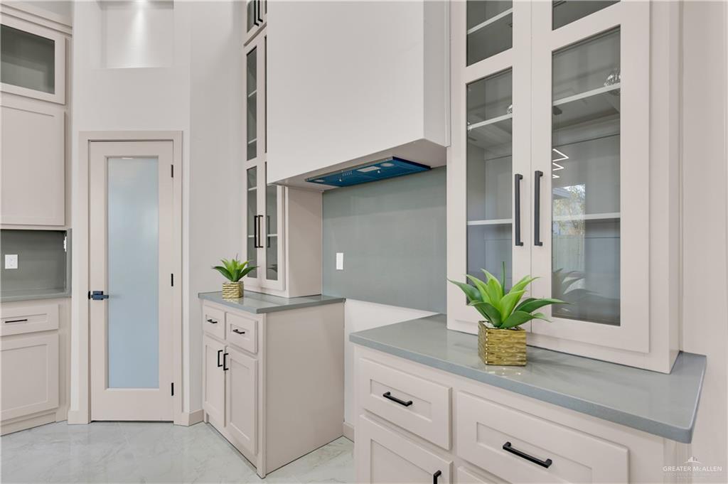 608 Spring Drive Alton, TX 78573 - Photo 13 of 32 Kitchen featuring white cabinetry, light marble finish flooring, and glass insert cabinets
