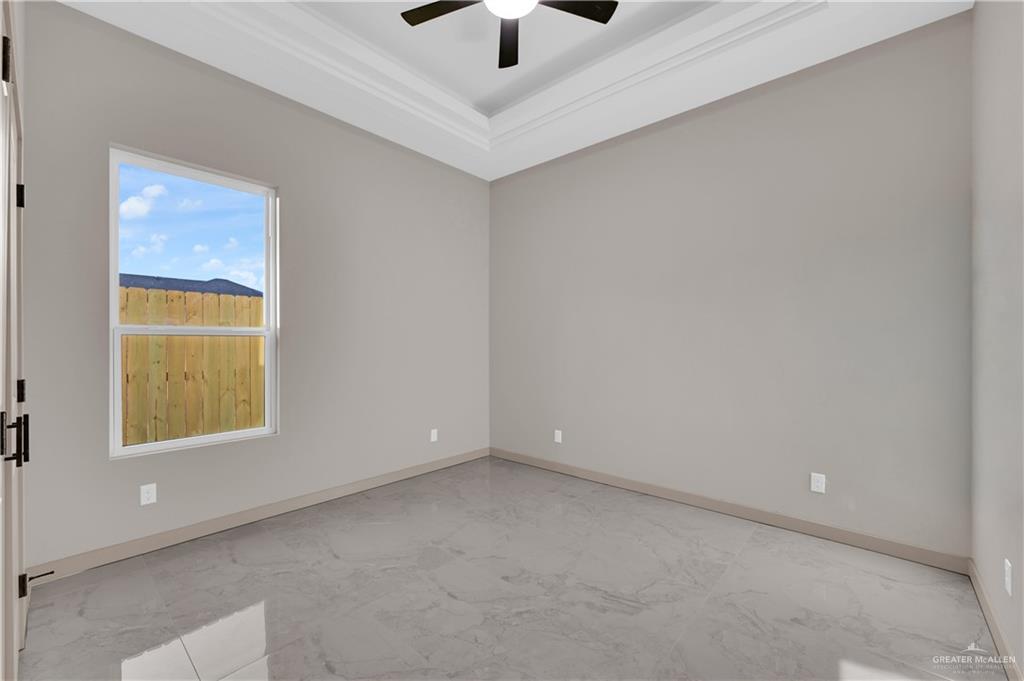 608 Spring Drive Alton, TX 78573 - Photo 14 of 32 Empty room featuring a tray ceiling, ornamental molding, and ceiling fan