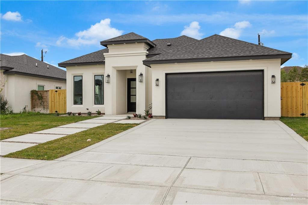608 Spring Drive Alton, TX 78573 - Photo 6 of 32 Prairie-style house with roof with shingles, driveway, stucco siding, an attached garage, and a gate