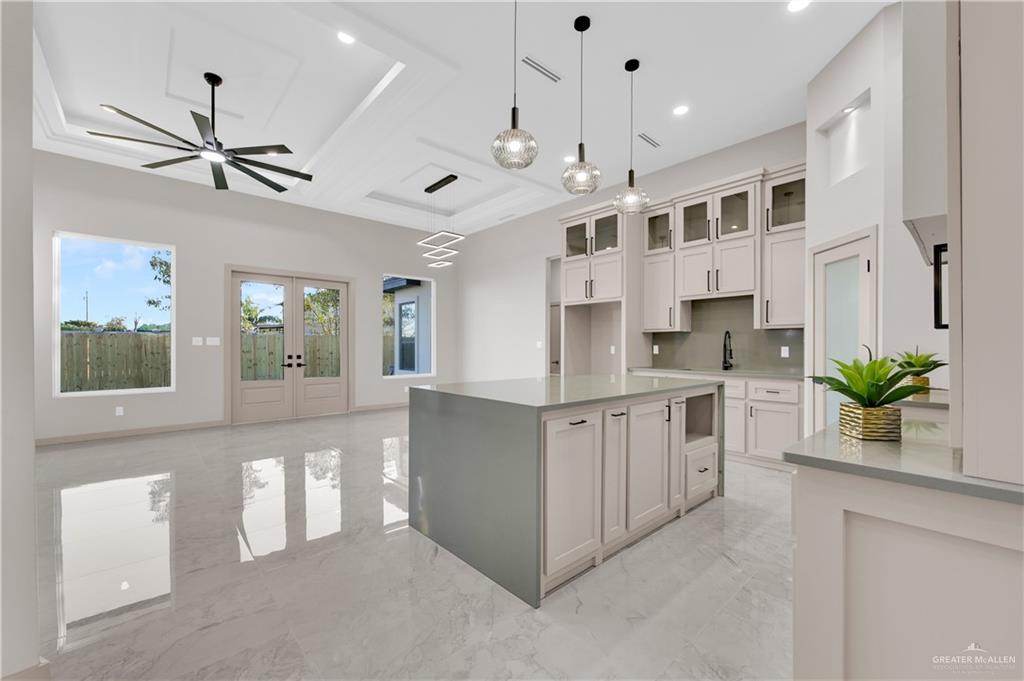 608 Spring Drive Alton, TX 78573 - Photo 7 of 32 Kitchen featuring french doors, a kitchen island, glass insert cabinets, light marble finish floors, and a ceiling fan