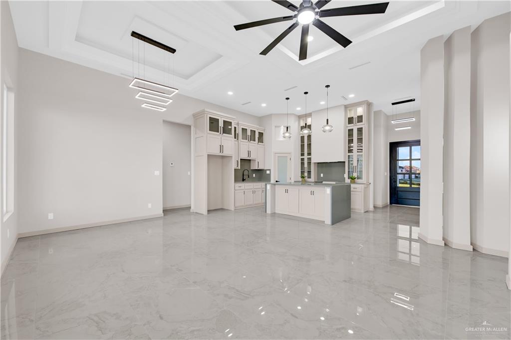 608 Spring Drive Alton, TX 78573 - Photo 9 of 32 Unfurnished living room featuring light marble finish flooring, a towering ceiling, a ceiling fan, a tray ceiling, and recessed lighting